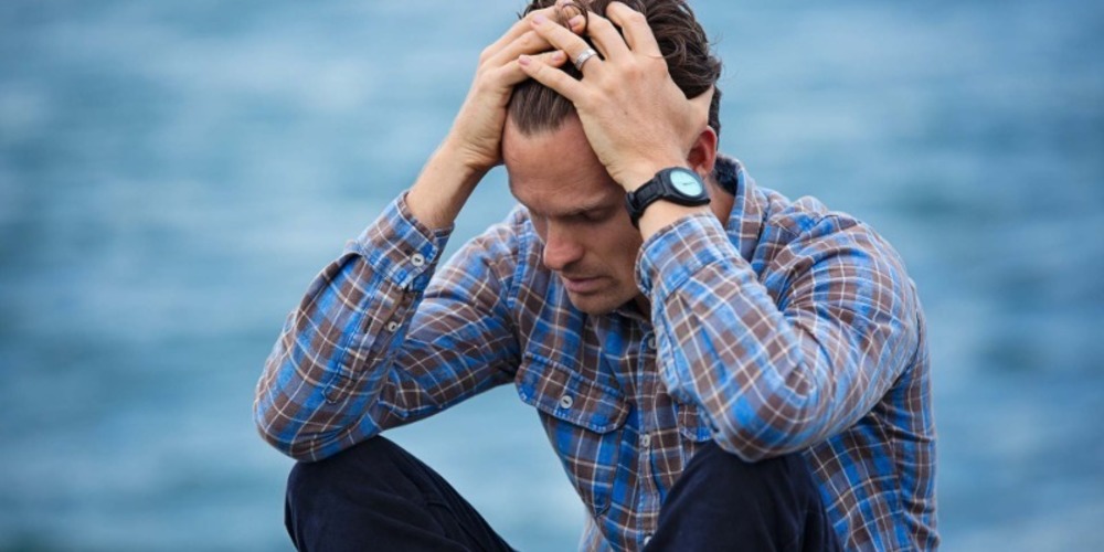 Blue Collar Worker Holding Head and Looking Visibly Stressed