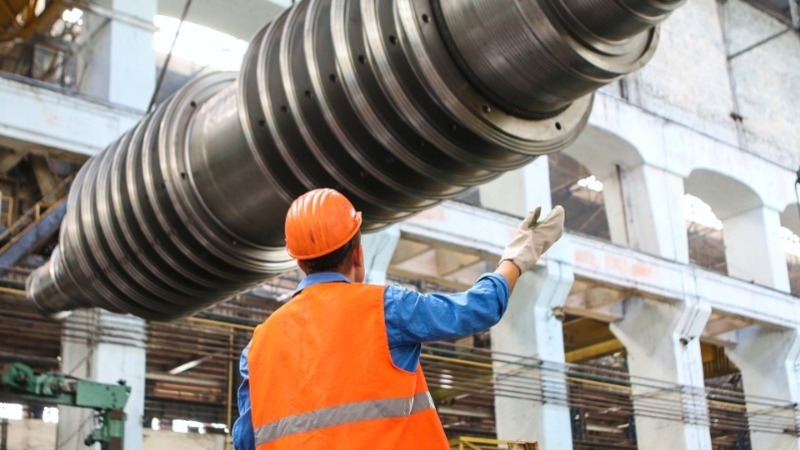 Photograph of Engineer Guiding a Moving Steel Part into Position